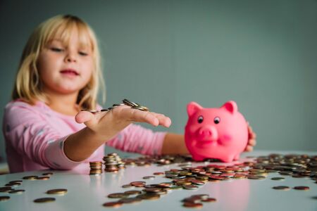 child saving money, cute girl put coins into piggy bankの写真素材