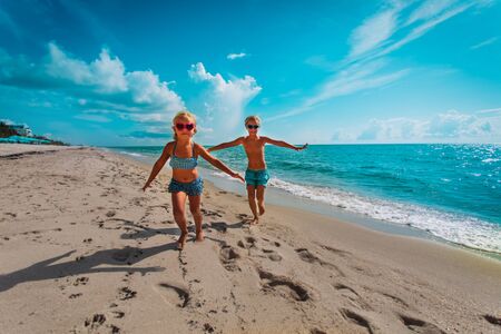 cute happy girl and boy running on beachの写真素材