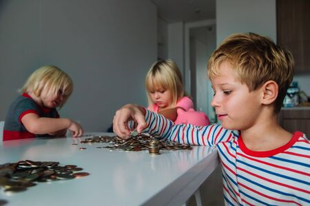 kids count money, boy and girls put coins into piggy bankの写真素材