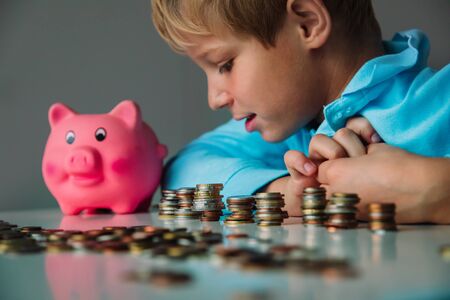 child saving money, boy put coins into piggy bankの写真素材