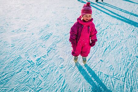 happy little girl learning to skate in winterの写真素材