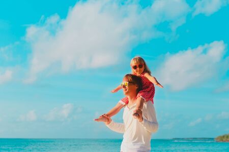happy father and little daughter play at sky on beach, family vacationの写真素材