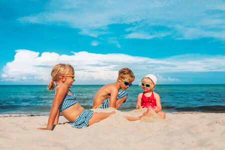 kids- boy and girls- play with sand on beachの写真素材