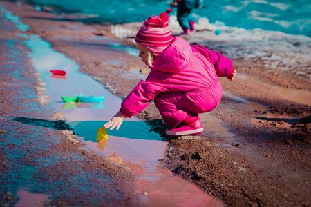 kids play with paper boats in spring puddleの写真素材