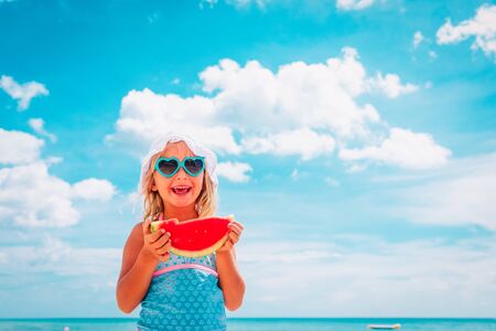 happy cute little girl eating watermelon at beachの写真素材
