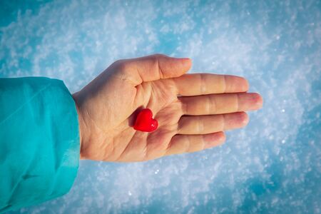 hand holding heart in winter snow nature, giving love, valentine conceptの写真素材