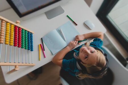 cute girl with headphones learning letters and counting with computer, online learning