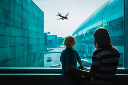 mother with little son looking at planes in airport, family travelの写真素材