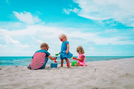 kids- boy and girls- play with sand on beachの写真素材