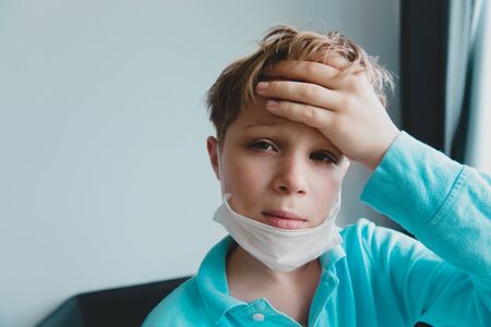Sick child with infection or virus, boy wearing mask on quarantine at homeの写真素材