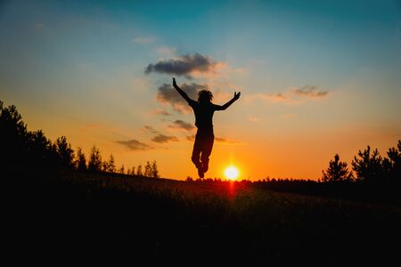 happy boy jumping at sunset sky, kid enjoy natureの写真素材