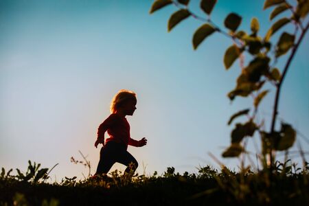 Silhouette of happy little girl running at sunset