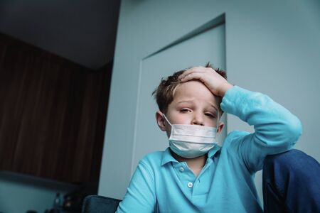 Sick child with infection or virus, boy wearing mask at homeの写真素材