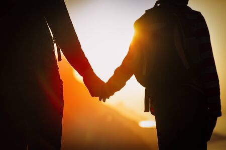 silhouette of father and son holding hands at sunset natureの写真素材