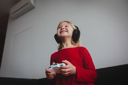 little girl playing video games at home, child with remote control indoorsの写真素材