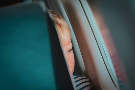little boy travel by plane looking through windowの写真素材