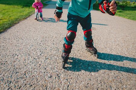 kid on roller skates and little girl on runbike outsideの写真素材