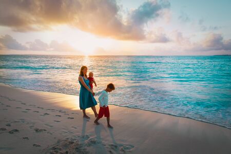 mother and kids walking on beach at sunset, family at seaの写真素材
