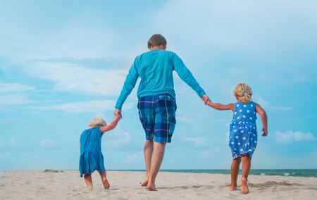 happy father and daughters play on beach, family have fun togetherの写真素材