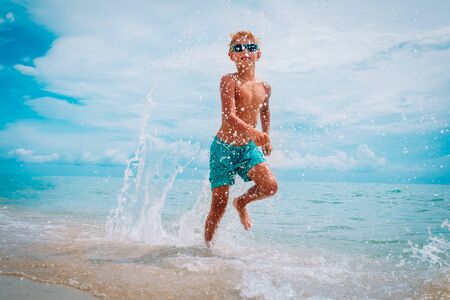 happy kid run and splash water on beachの写真素材