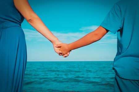 mother and son holding hands on beach