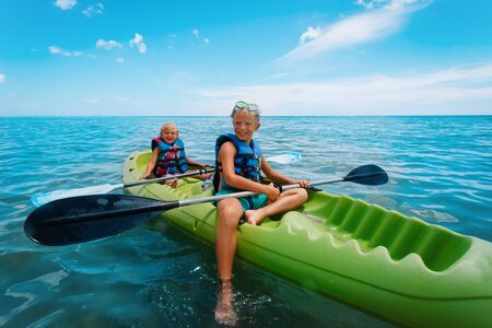 happy girl and boy kayaking on beach vacationの写真素材