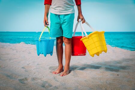 kid holding toys on beach, boy ready to dig and play with sand, summer activities for kidsの写真素材