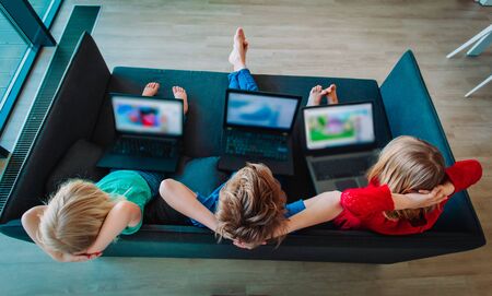 kids with laptops at home, boy and girls watching movies onlineの写真素材