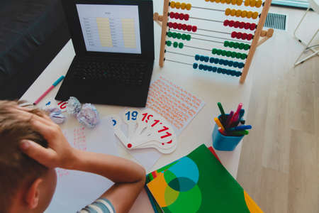 Kid bored of doing her homework with laptop at home. Education and distance learning for kids. Homeschooling during quarantine.の写真素材