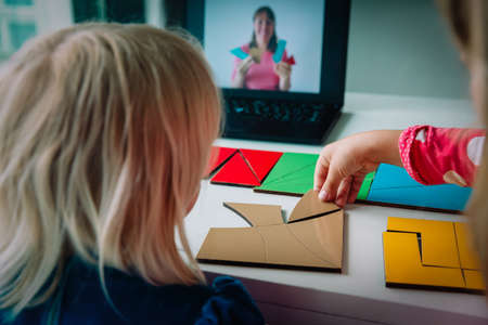 kids play with puzzle, doing tangram, learning shapes with online lessonの写真素材