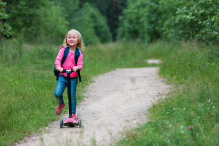 happy active kid on scooter ride in natureの写真素材