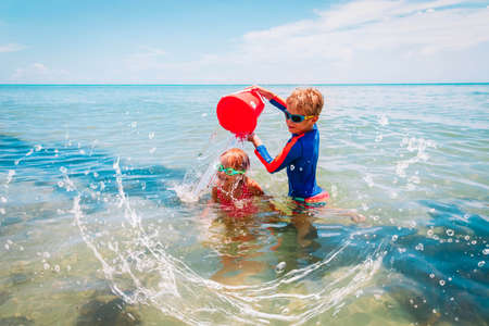 happy boy and girl play on beach, kids splash water and have funの写真素材