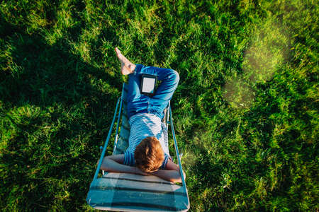 boy relax in nature and reading book, kid summer learningの写真素材