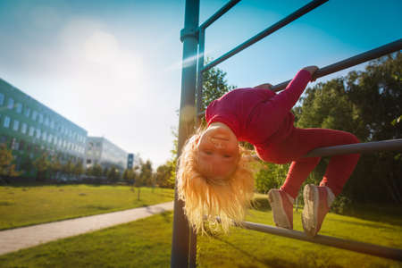 happy cute little girl upside down on monkey barsの写真素材