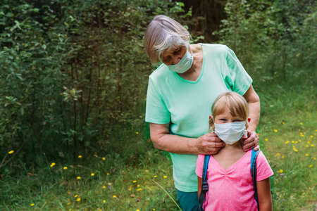 grandmother put mask on child before going to schoolの写真素材