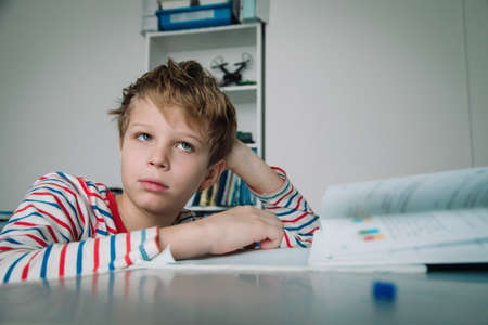 Child looking puzzled, kid tired and bored of doing homeworkの写真素材