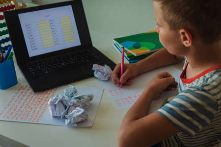 Kid doing her homework with laptop at home.の写真素材