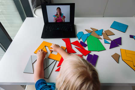little girl play with puzzle, doing tangram, learning with online lessonの写真素材
