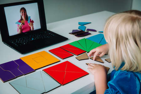 little girl play with puzzle, doing tangram, learning with online lessonの写真素材