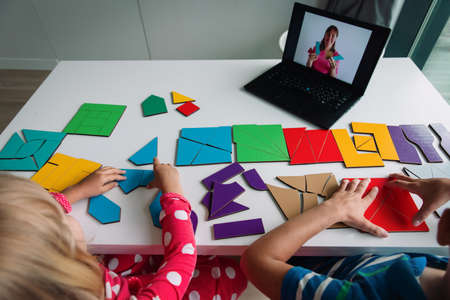kids play with puzzle, doing tangram, learning shapes with online lessonの写真素材