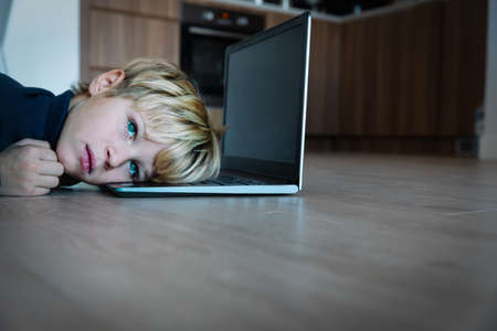 Bored and sad teenager looking at computer, kid tired of online learningの写真素材