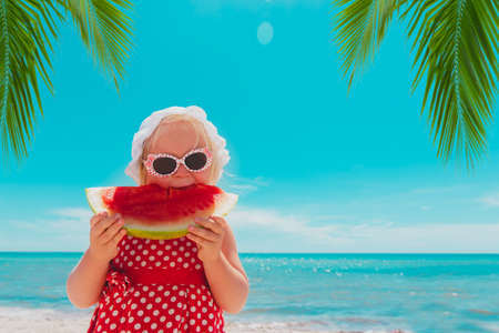 happy cute little girl eating watermelon on beachの写真素材