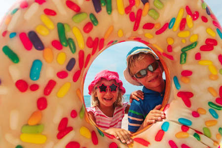 happy cute boy and girl play with floatie on beachの写真素材