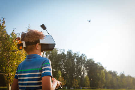 boy flying drone in virtual reality glasses in nature