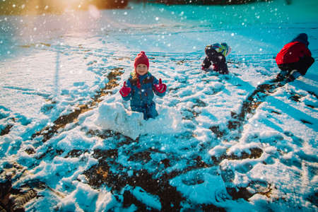 kids play in winter snow, family building from snow