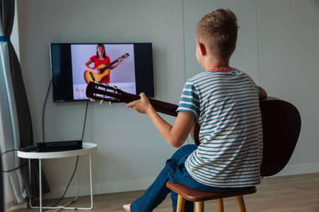 young boy having guitar lesson online at homeの写真素材