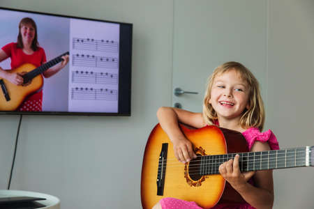 cute girl having guitar lesson online at homeの写真素材