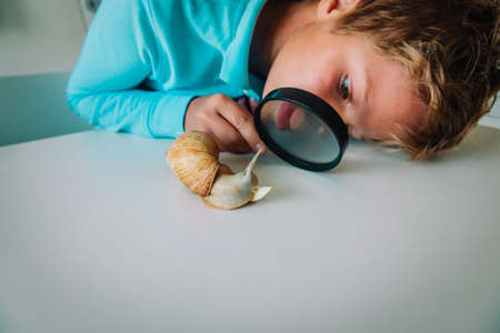 boy looking at giant snail through magnifying glass
