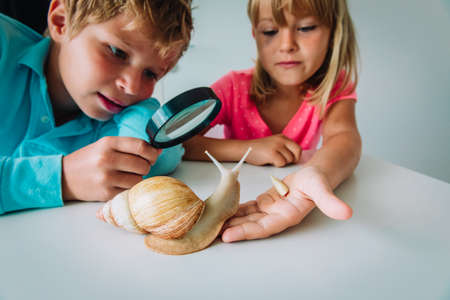 boy and girl looking at giant snail through magnifying glass