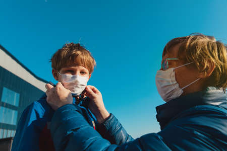 Father puts a medical mask on son outdoorsの写真素材